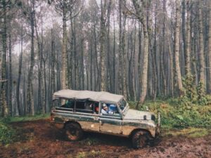 Land Rover sedang offroad di alam terbuka, melintasi medan yang menantang dengan semangat petualangan.